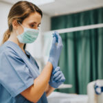 Female,Nurse,With,A,Mask,Putting,On,Gloves