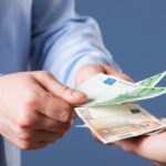 Businessman counting euro banknotes, blue background